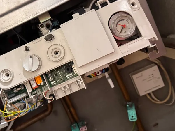 Combi boiler with the front removed showing the pressure gauge and controls